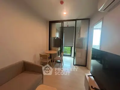 Modern living room with open kitchen and balcony view, featuring cozy furniture and natural light.