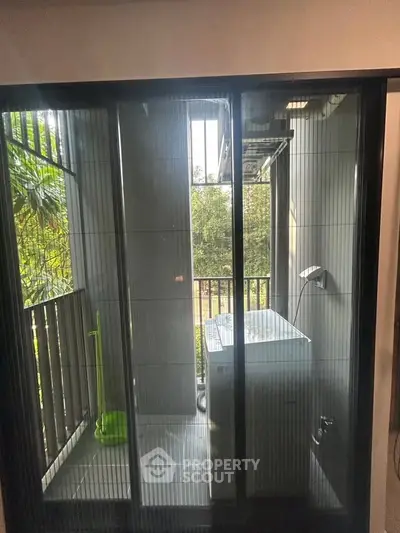 Charming balcony with washing machine and lush greenery view, perfect for urban living convenience.