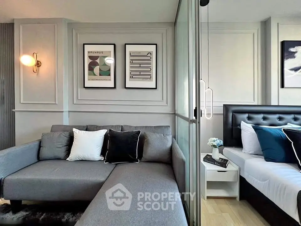 Modern living room with stylish decor and cozy bedroom separated by glass partition