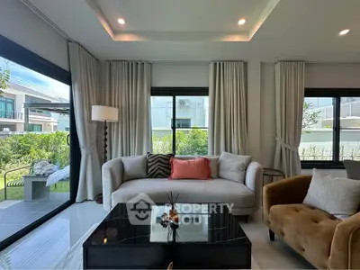 Elegant living room with modern decor and large windows offering garden views in a luxury home.