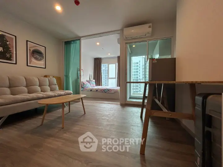 Modern apartment interior with open living room and bedroom, featuring stylish decor and city view.