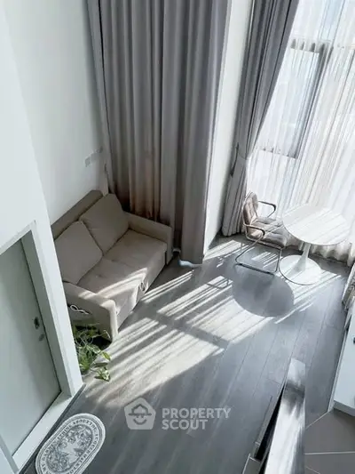 Modern living room with high ceilings and large windows, featuring a cozy sofa and stylish decor.