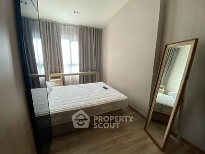 Cozy bedroom with natural light, wooden flooring, and a full-length mirror for a modern touch.