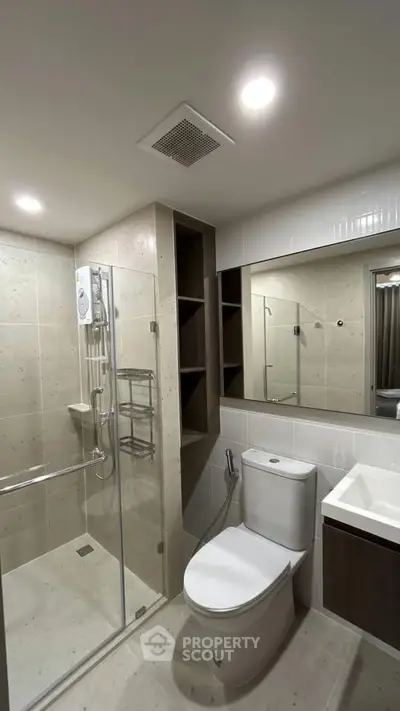 Modern bathroom with glass shower, sleek fixtures, and ample storage space.
