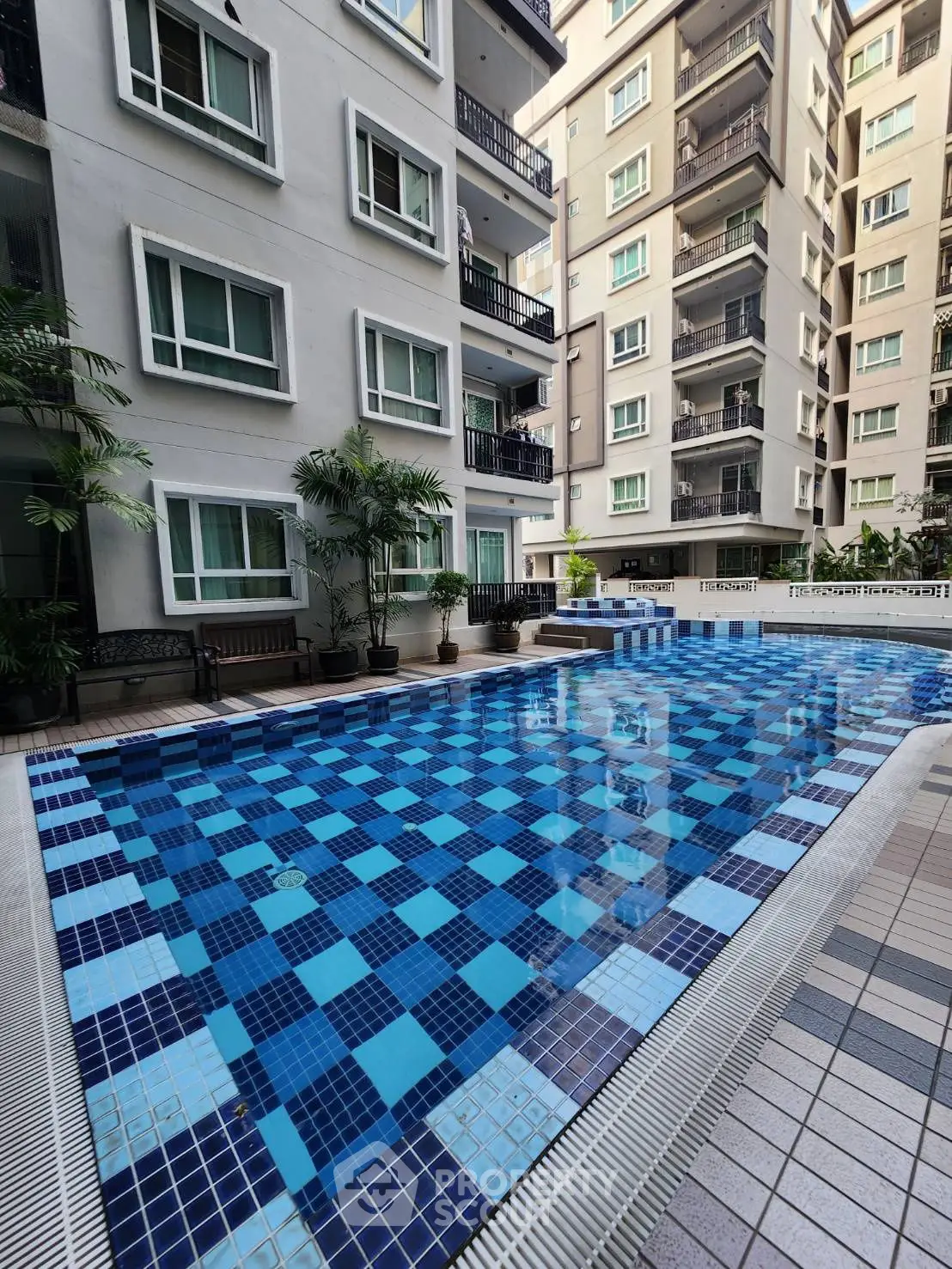 Modern apartment complex with a spacious swimming pool and lush greenery