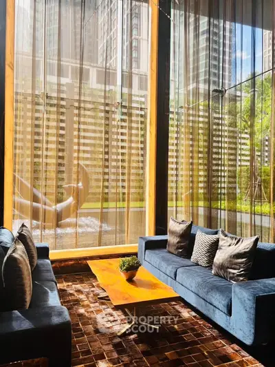 Luxurious living room with floor-to-ceiling windows and stunning city view, featuring elegant blue sofas and a chic coffee table.