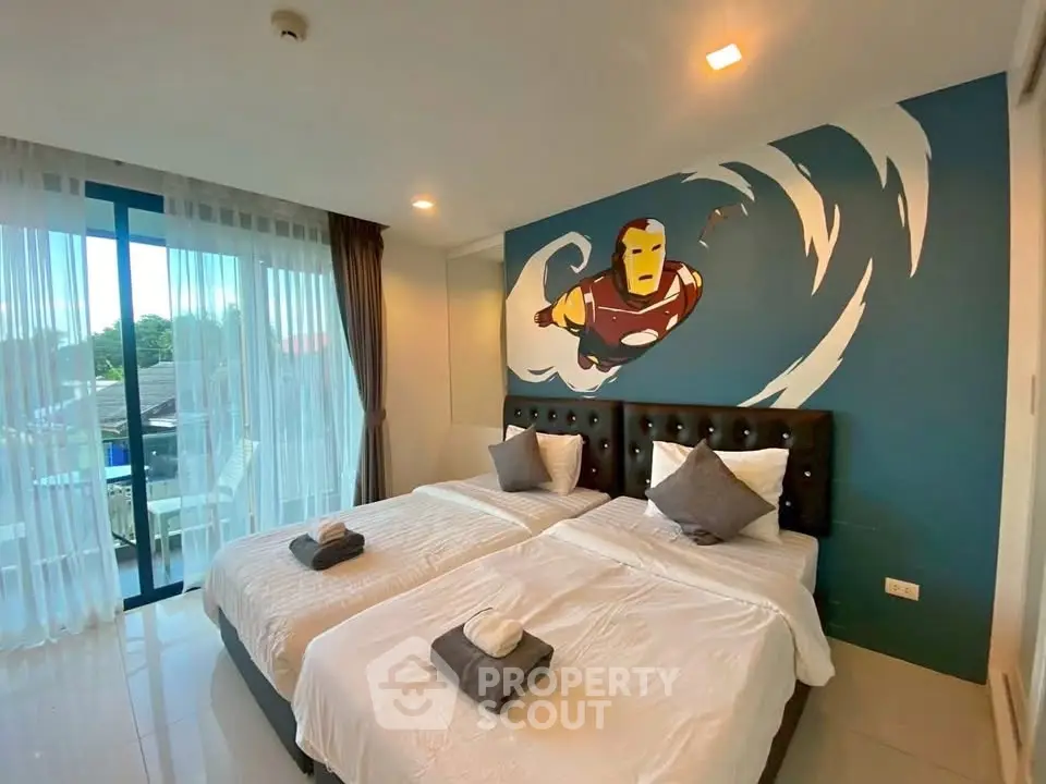 Modern bedroom with twin beds and superhero wall art, featuring large windows and natural light.