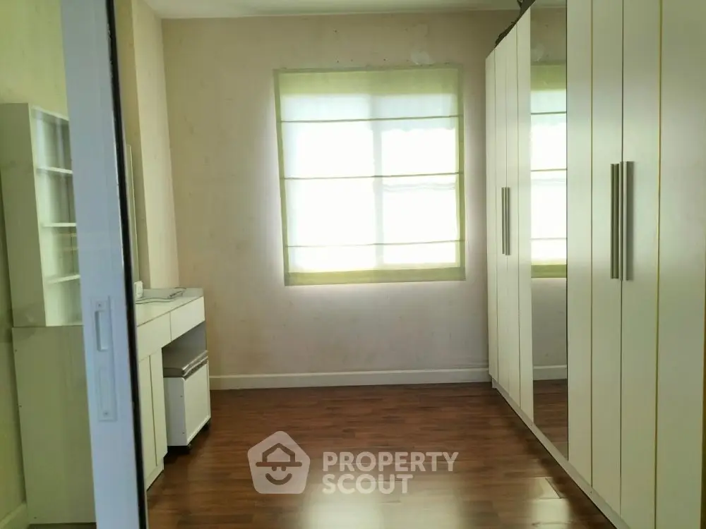 Spacious bedroom with large wardrobe and wooden flooring, perfect for modern living.