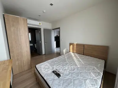 Modern bedroom with wooden flooring and built-in wardrobe, featuring a comfortable bed.