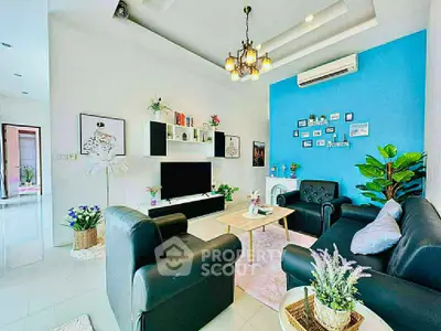 Stylish modern living room with black leather sofas, vibrant blue accent wall, and elegant lighting.