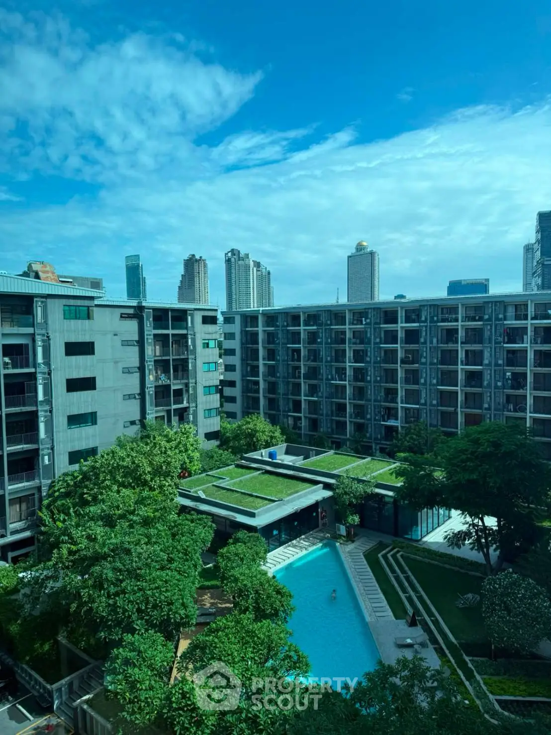Modern urban apartment complex with pool and lush greenery, offering a serene city living experience.