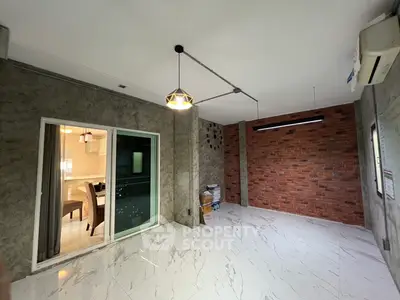 Modern interior with exposed brick wall and marble flooring, adjacent to a sleek kitchen area.