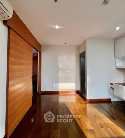 Spacious modern living room with wooden flooring and sliding door, perfect for stylish living.