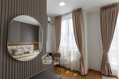 Elegant bedroom with modern decor, featuring a round mirror and soft lighting, perfect for a cozy retreat.