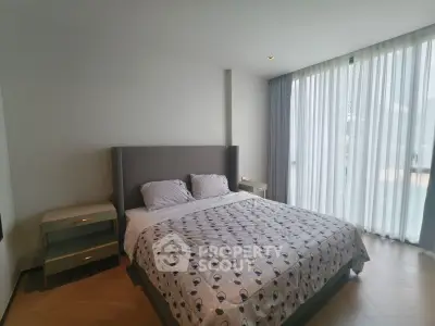 Spacious bedroom with modern decor and large window for natural light.