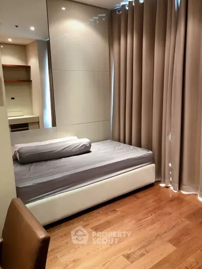 Cozy bedroom with wooden flooring and modern decor, featuring a comfortable bed and elegant curtains.