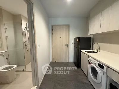 Modern apartment entry with compact kitchen and bathroom, featuring sleek appliances and minimalist design.