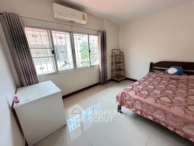 Bright bedroom with large window and air conditioning, featuring a cozy bed and minimalist decor.