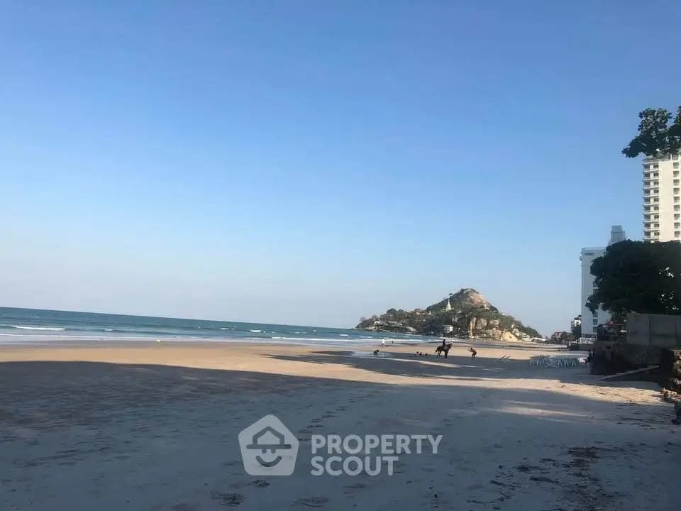 Scenic beachfront view with clear skies and distant buildings, perfect for coastal living.