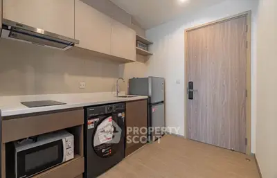 Modern kitchen with appliances including washing machine, microwave, and fridge in a compact layout.