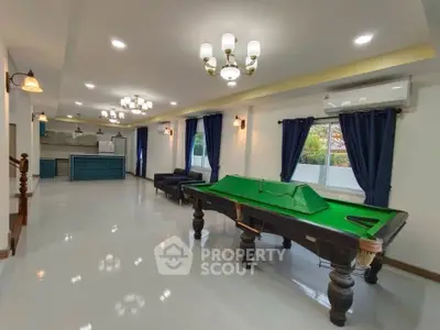 Spacious living room with pool table and modern kitchen in open layout