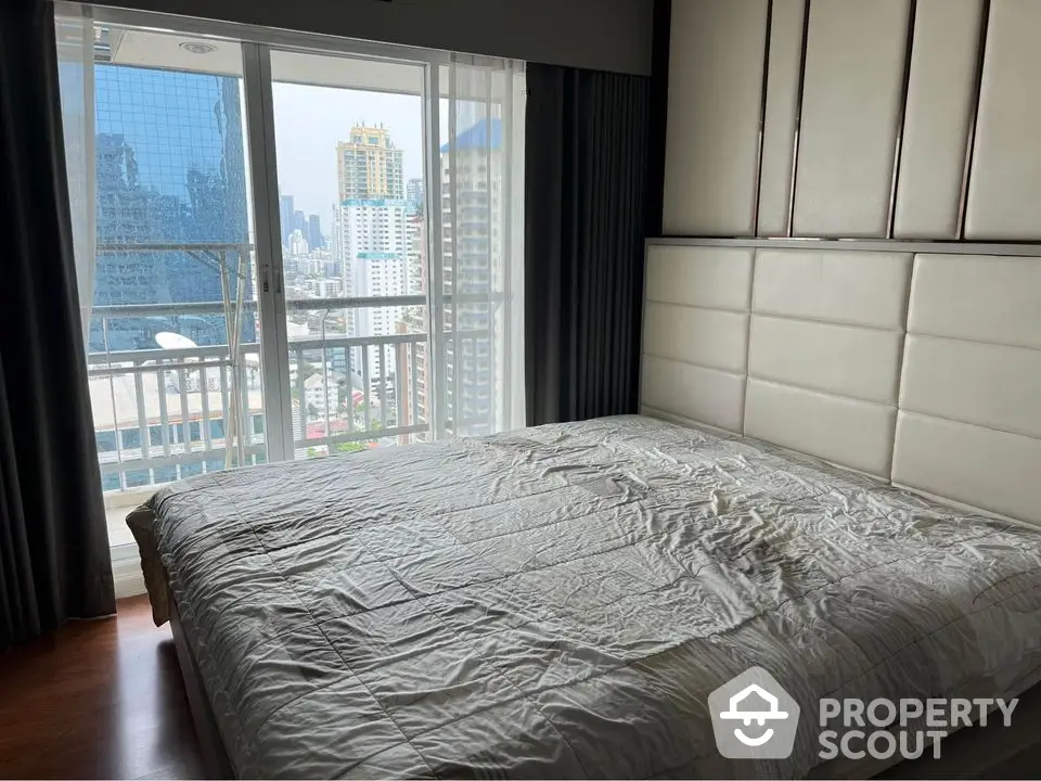 Modern bedroom with city view and large windows in high-rise apartment