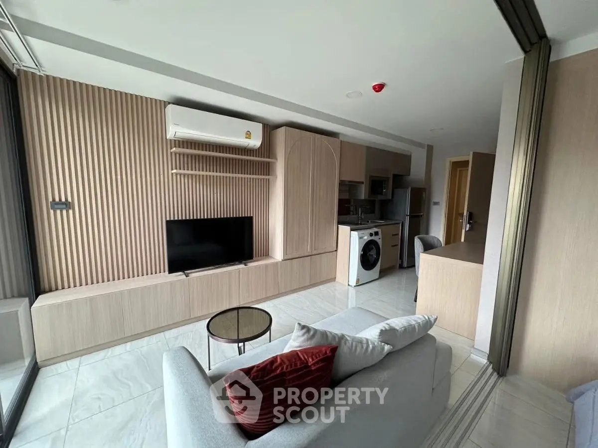Modern living room with sleek design, featuring a washing machine and open kitchen layout.