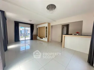 Spacious modern living room with elegant chandelier and large windows offering natural light.