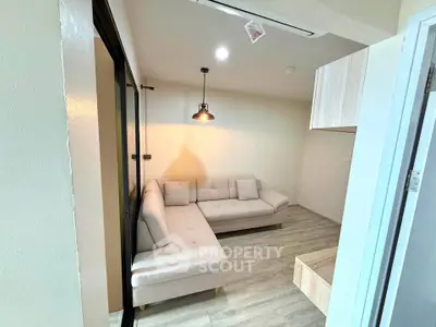 Modern living room with cozy L-shaped sofa and stylish lighting in a compact apartment.