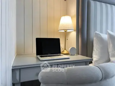Cozy bedroom corner with elegant desk, lamp, and laptop setup.