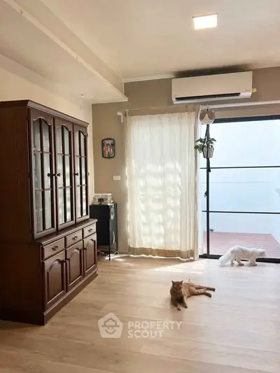 Spacious living room with wooden cabinet and natural light, featuring elegant flooring and modern air conditioning.