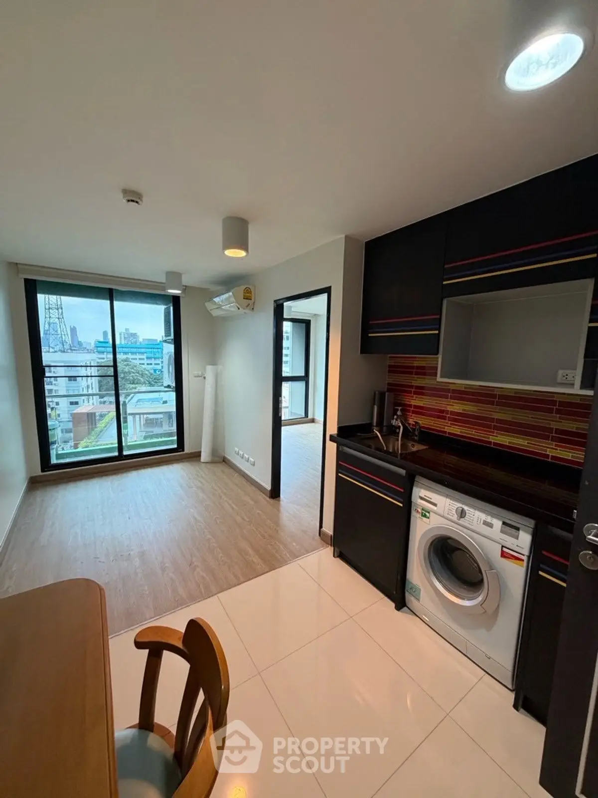 Modern apartment with city view, open layout kitchen, and washing machine.