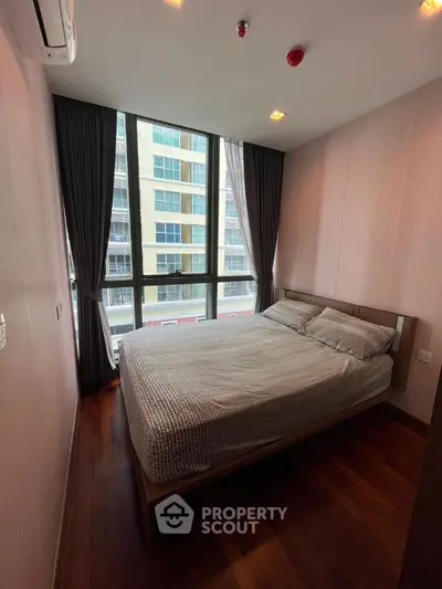 Modern bedroom with large windows and city view in high-rise apartment