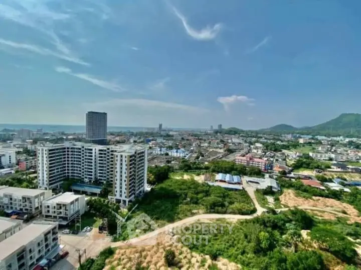 Stunning cityscape view from high-rise building with lush greenery and clear blue sky.