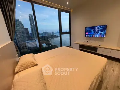 Luxurious bedroom with stunning city and ocean view, featuring modern decor and wall-mounted TV.