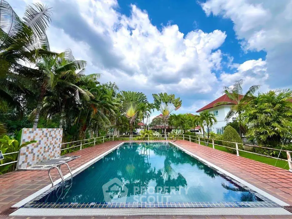 Stunning outdoor pool with lush greenery and clear blue sky, perfect for relaxation.