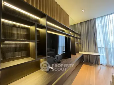 Modern living room with built-in shelving and large TV, featuring elegant lighting and floor-to-ceiling windows.