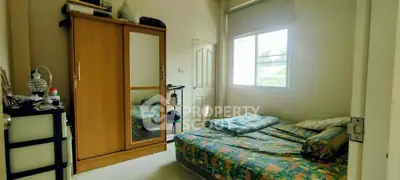 Cozy bedroom with natural light, featuring a wardrobe and a comfortable bed.