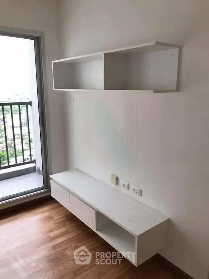 Modern minimalistic living room with balcony view and sleek white shelving unit.