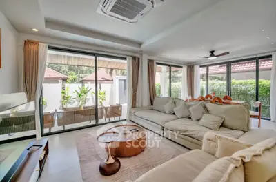 Spacious living room with large windows and garden view, featuring modern furniture and elegant decor.