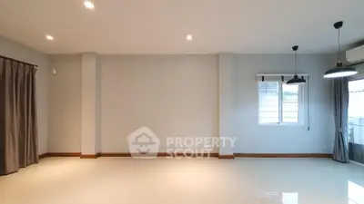 Spacious unfurnished living room with modern lighting and large windows.