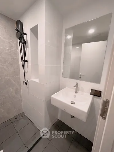 Modern bathroom with sleek design, featuring a wall-mounted sink and large mirror.