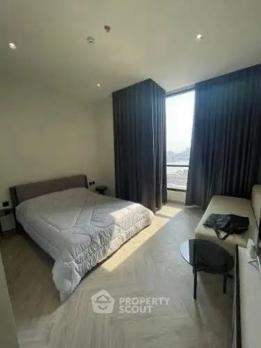 Modern bedroom with large window and stylish furnishings in a bright apartment.