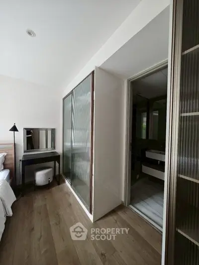 Modern bedroom with sliding closet doors and adjacent bathroom entrance.