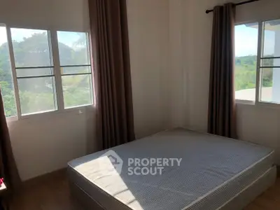 Bright bedroom with large windows and scenic view, perfect for relaxation.
