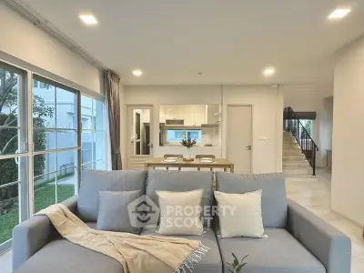 Spacious modern living room with open kitchen and garden view, perfect for family gatherings.