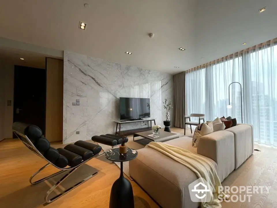 Luxurious living room with marble wall accents, modern furniture, and floor-to-ceiling windows offering ample natural light.