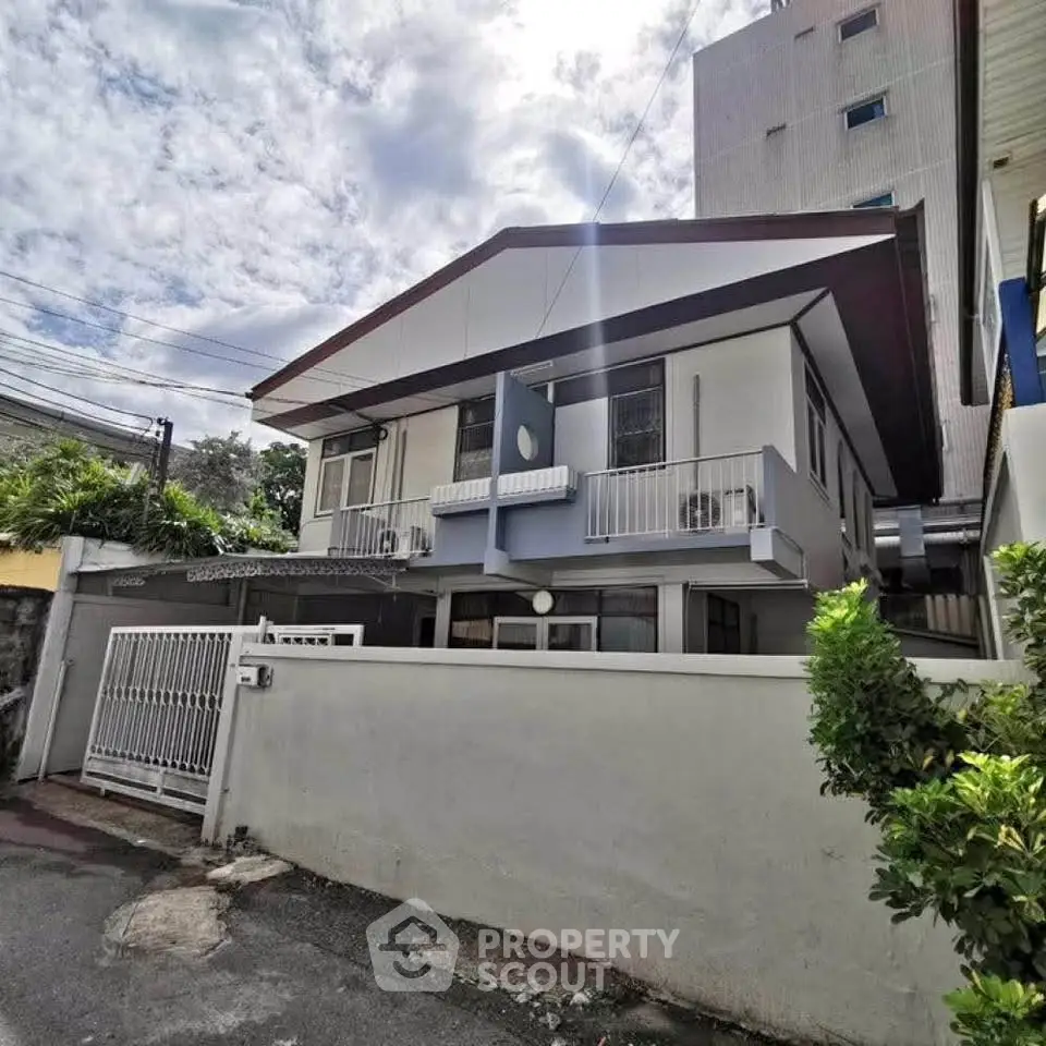Charming two-story house with modern facade and small balconies, nestled in a quiet neighborhood.