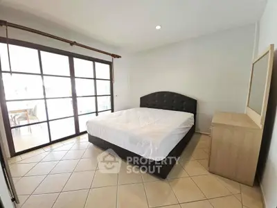Spacious bedroom with large windows and modern furnishings in a bright apartment.