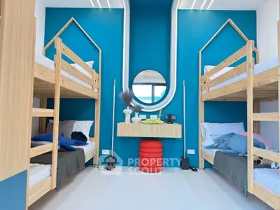 Modern bedroom with bunk beds and vibrant blue accent wall, ideal for shared living spaces.